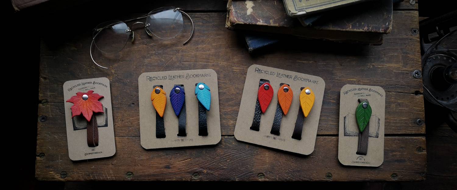 Colorful Recycled Leather Leaf and Feather Bookmarks laying on a wooden crate